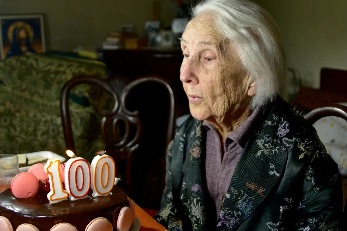 Woman blowing out a “100” birthday candle