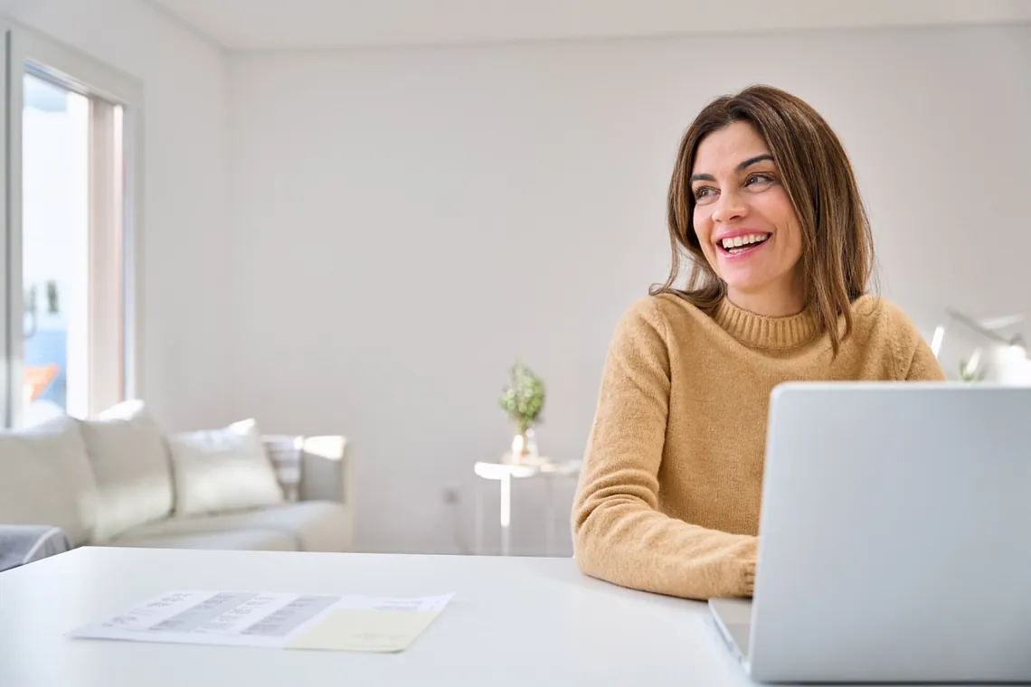 Happy middle-aged woman working on a laptop