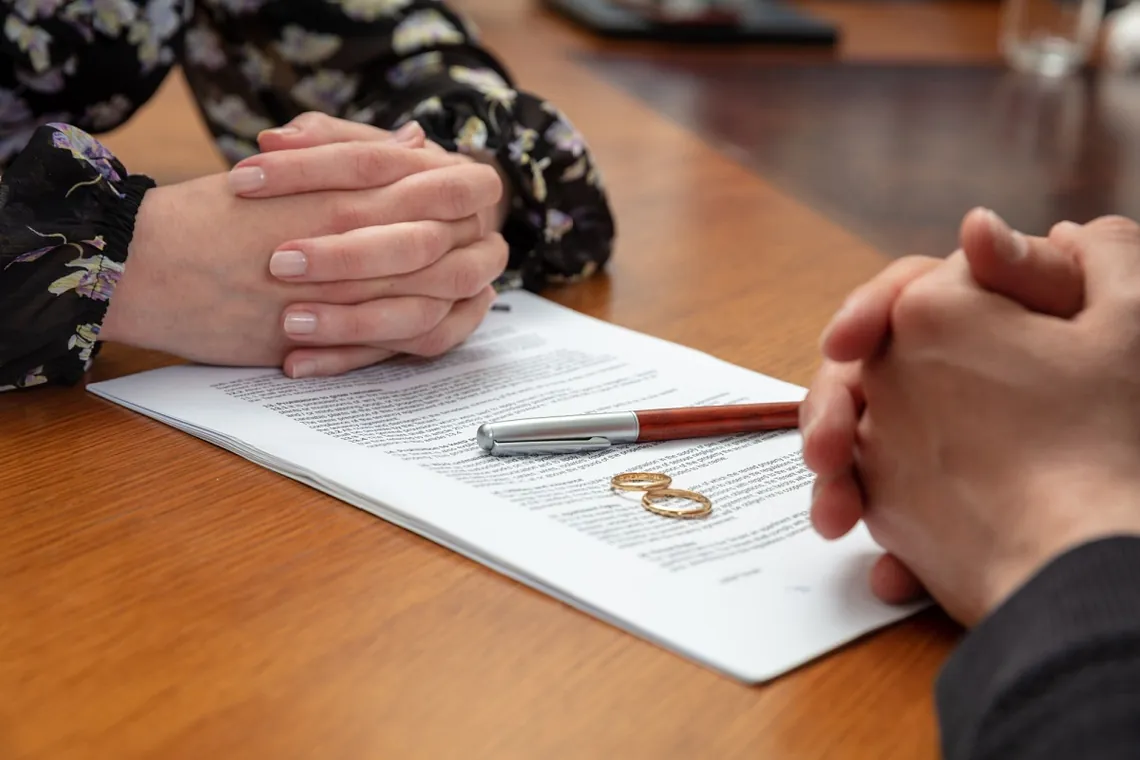 Male and female hands, divorce document and rings